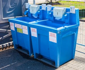 two portable hand wash stations next to a porta potty[